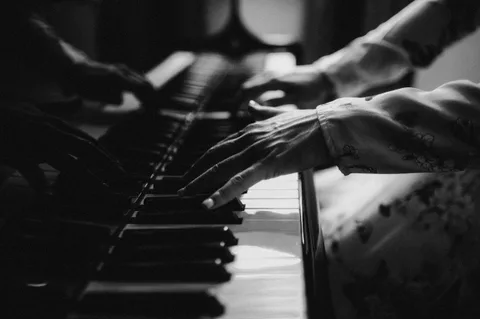 Black-and-white close study of Mekhriban Mamedova's hands playing the piano keys.